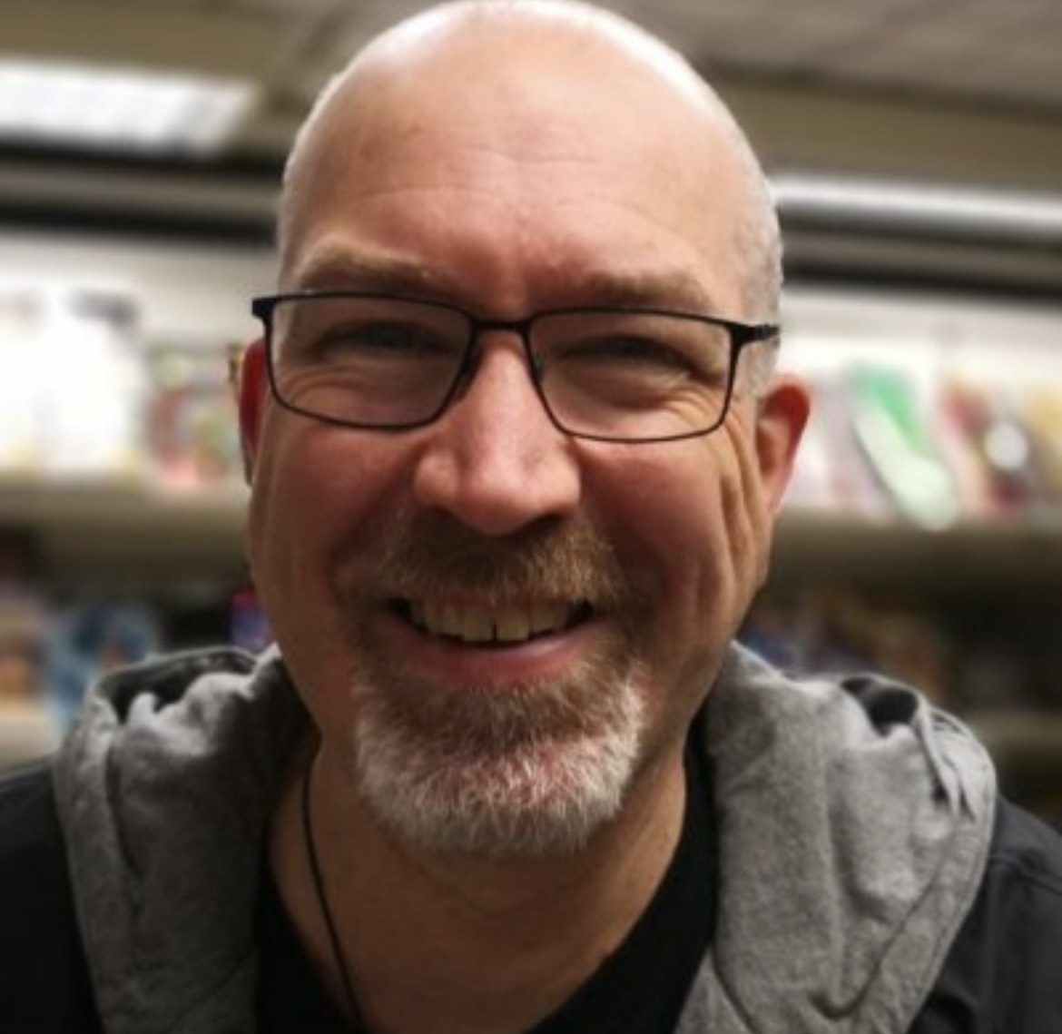 Padraig Hogan smiling in front of bookshelves